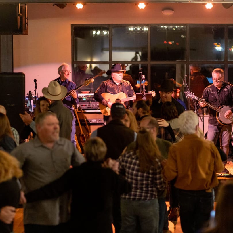 A country band performs on stage while people dance at The Jump Restaurant & Bar.