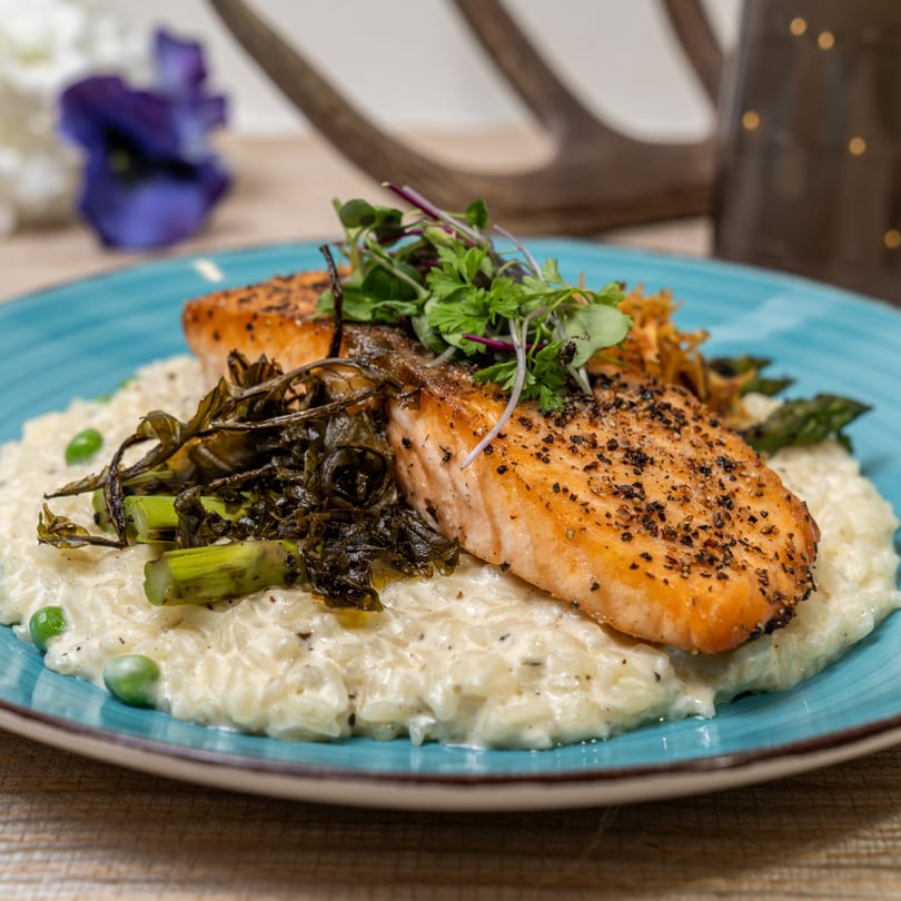 Pan-seared salmon with black pepper, served over creamy risotto with peas and asparagus.
